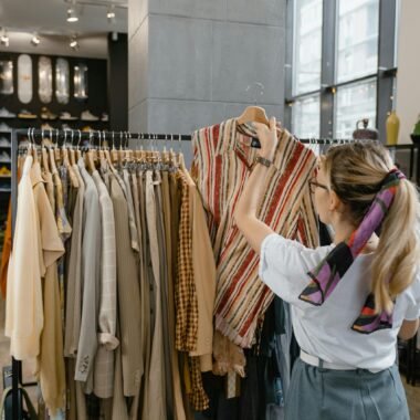 A woman browses clothes on a rack inside a stylish fashion boutique.