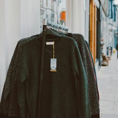 Sweaters displayed on a clothing rack outside a shop, perfect for street shopping environments.