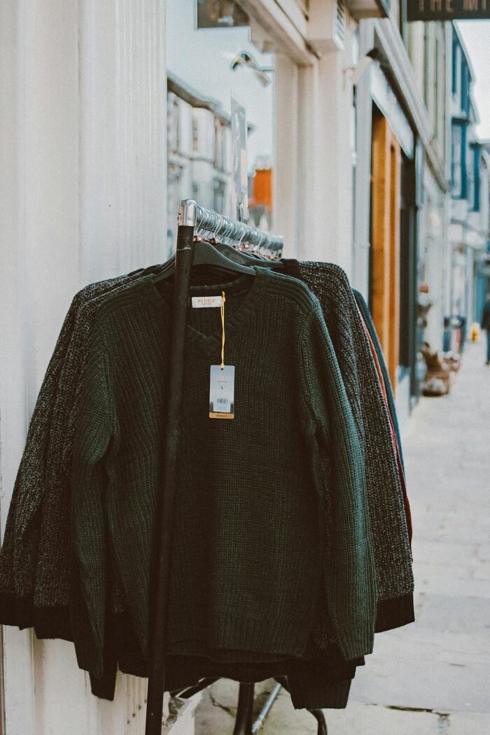 Sweaters displayed on a clothing rack outside a shop, perfect for street shopping environments.