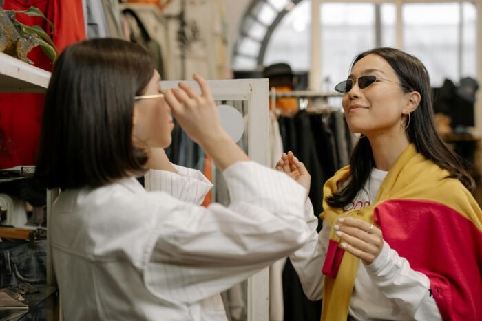 Two stylish women trying on sunglasses in a trendy boutique, enjoying a fashion shopping experience.