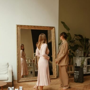 Two women shopping and trying on clothes indoors with a large ornate mirror.